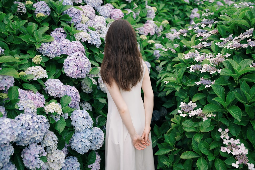 a woman standing in front of a bunch of flowers