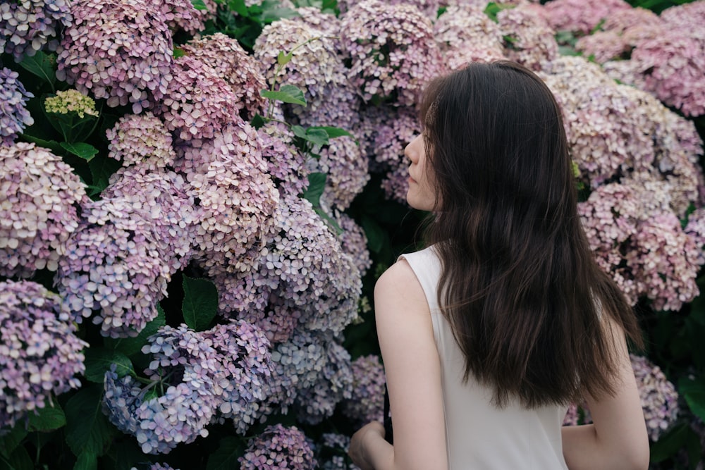 a woman standing in front of a wall of flowers