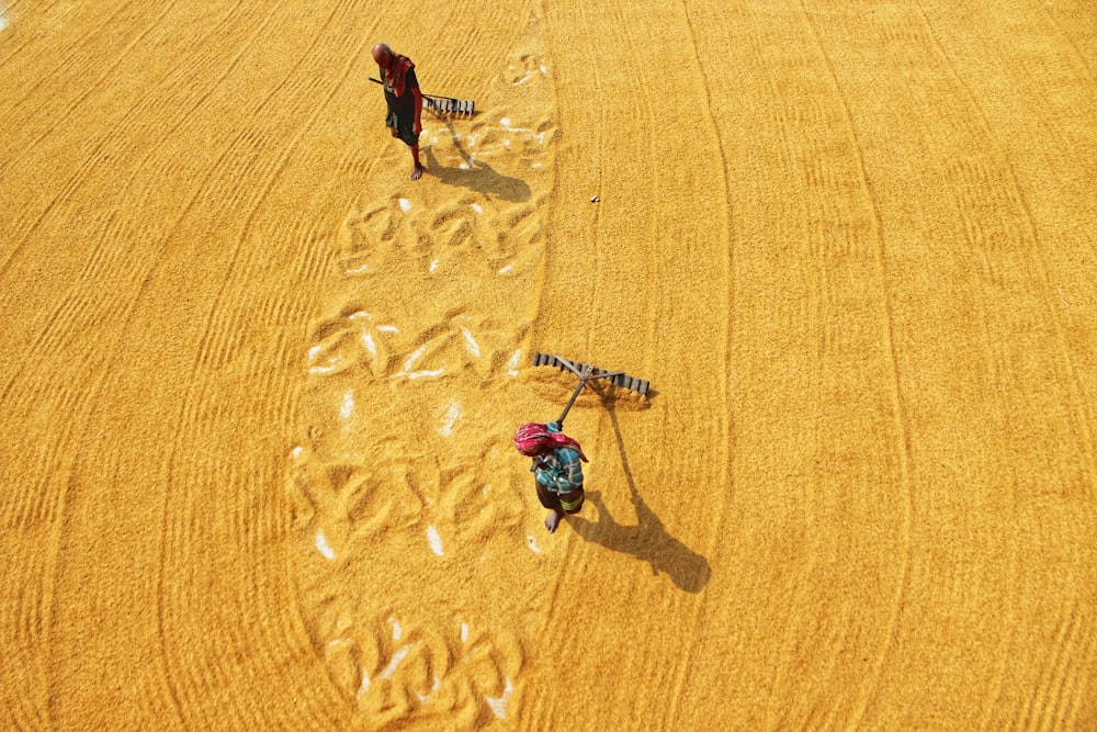 a couple of people walking across a dry grass field