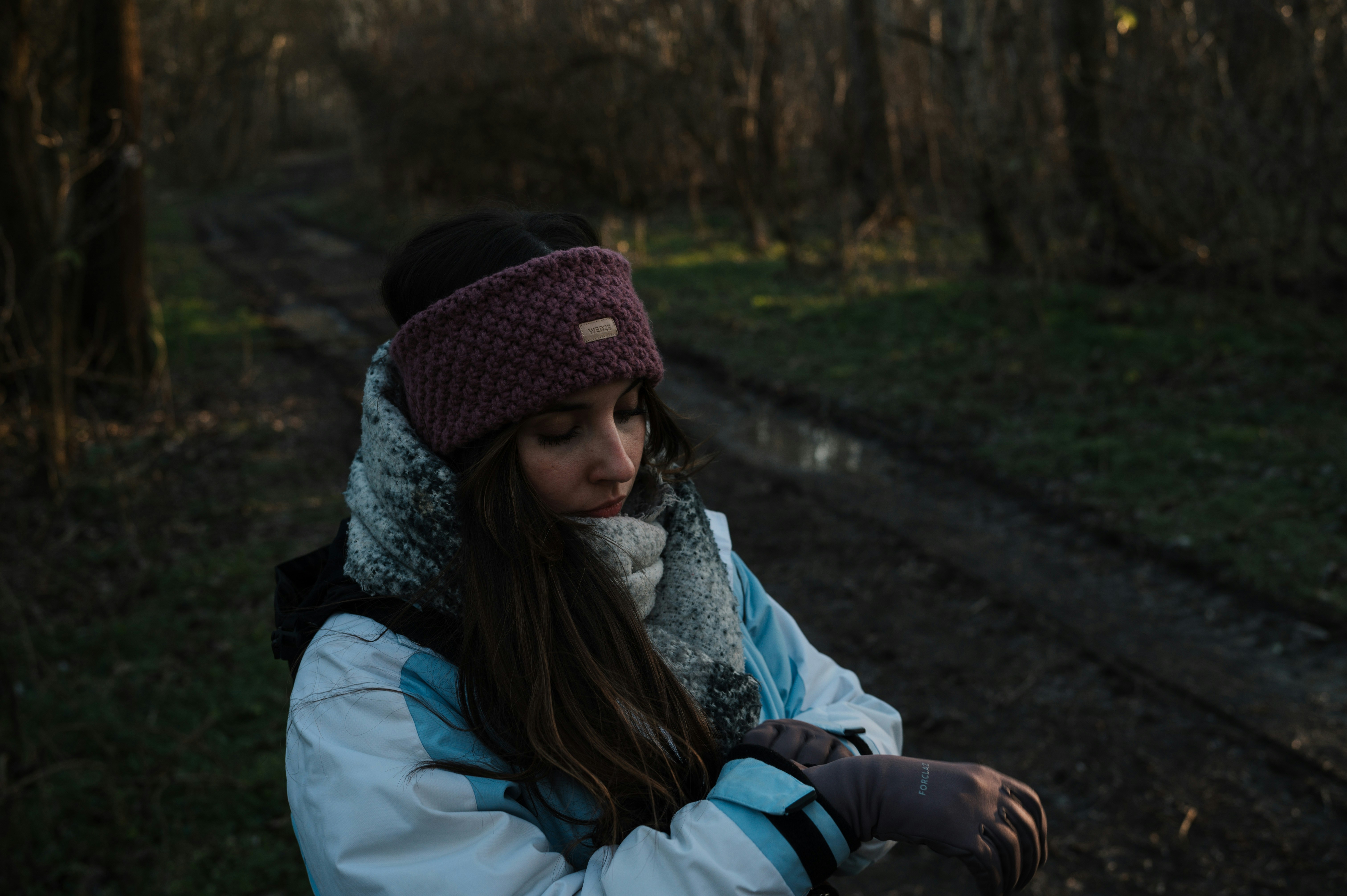 A runner in cold-weather headwear and gloves on a wooded winter trail