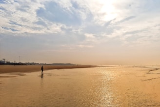 Traveller walking by the sea at sunrise on a peaceful beach