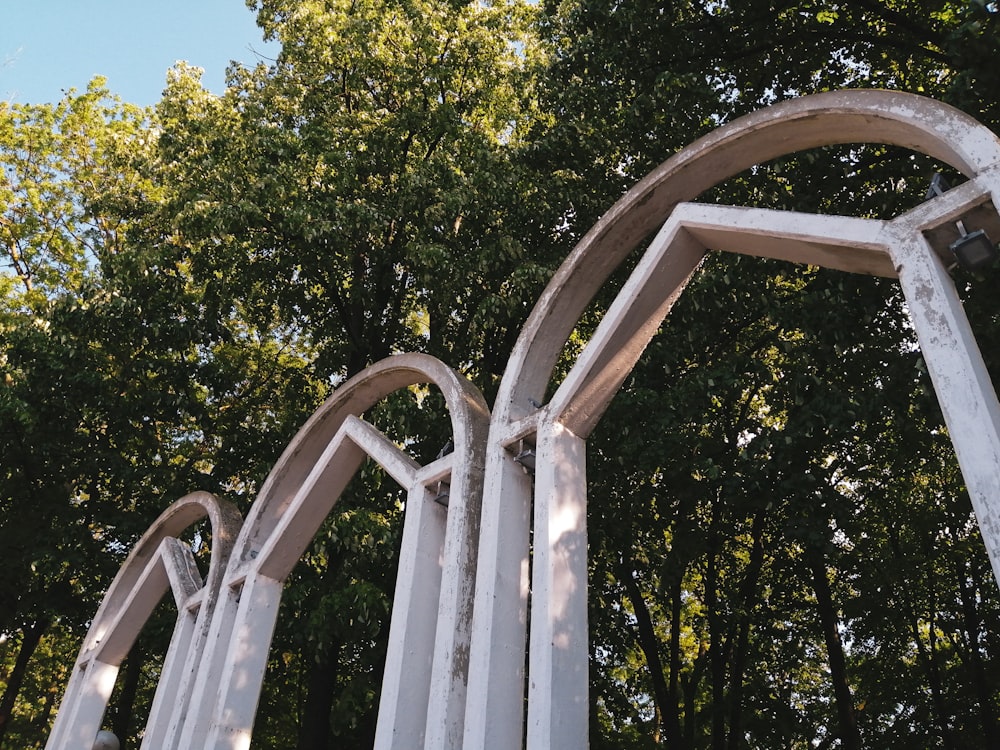 a white metal sculpture with trees in the background