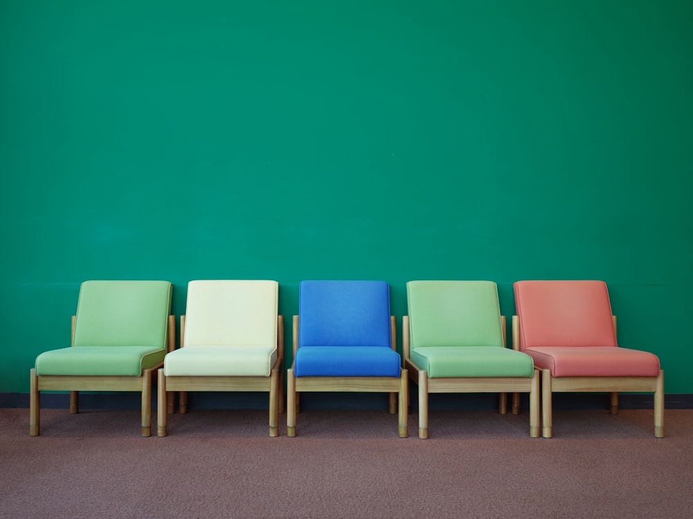 a row of colorful chairs against a green wall