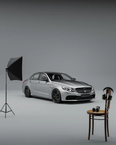 A photographer capturing a sleek car on a rotating turntable under bright studio lights.