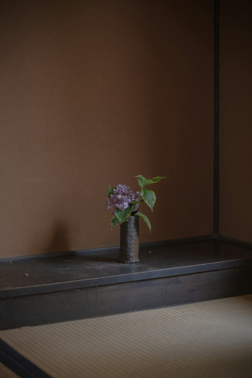 a small vase with a purple flower in it
