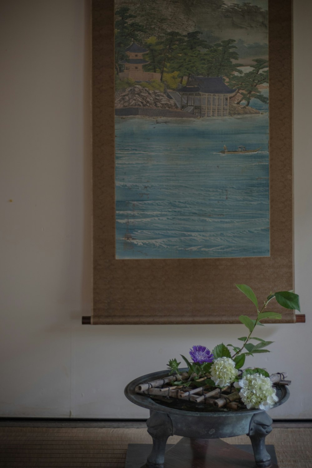 a painting hanging on a wall above a vase with flowers in it