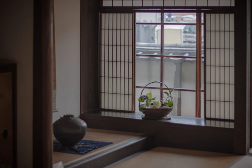 A serene Japandi living room featuring light wood furniture, soft linen cushions, and natural stone accents bathed in gentle sunlight.