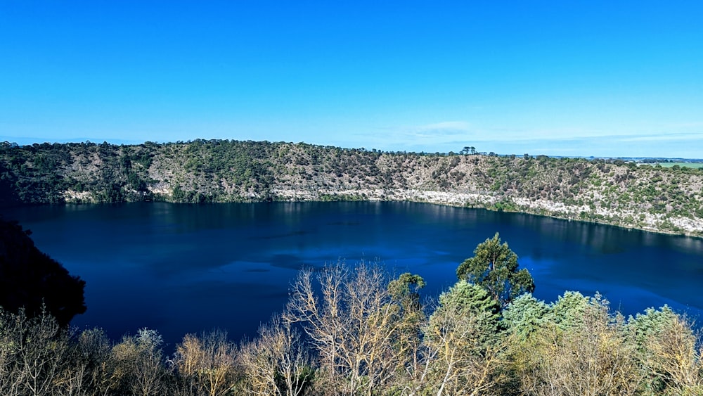 a blue lake surrounded by trees on a sunny day