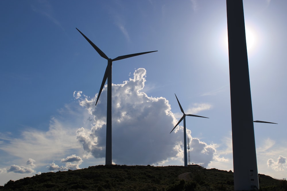 a group of windmills on a hill under a blue sky