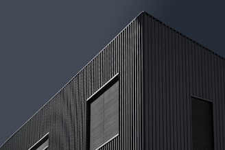 Modern architectural exterior of a sleek office building with dark tones and sharp lines.