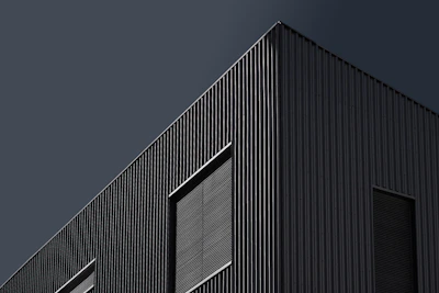 Elegant office building facade featuring glass and steel with a dark color palette.