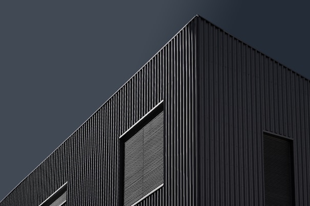 Modern architectural exterior of a sleek office building with dark tones and sharp lines.