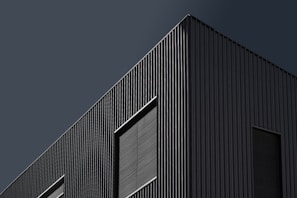 A sleek industrial factory exterior showcasing clean lines and minimalist design in deep charcoal tones.