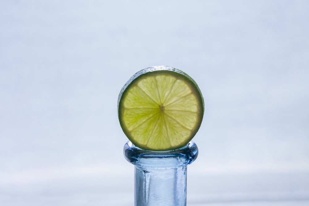 a lime slice sitting on top of a glass bottle