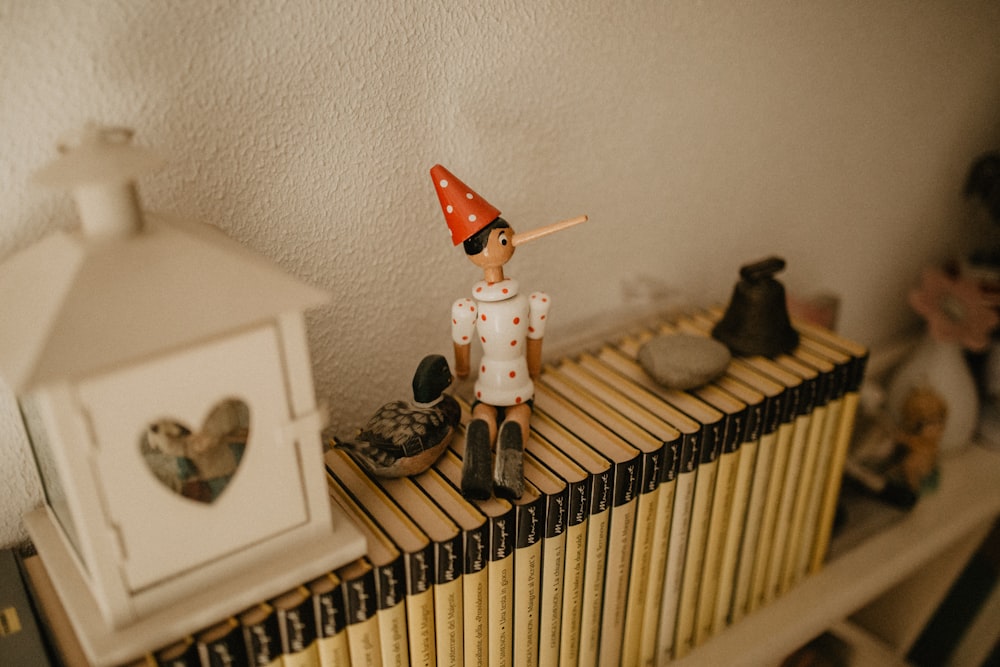 una pequeña figurita sentada encima de un estante de libros