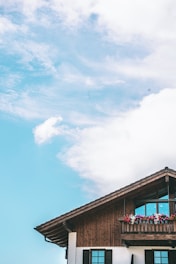 A beautifully restored house facade with a newly built wooden terrace under a clear sky.