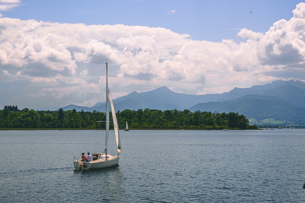 Una barca a vela nel mezzo di un lago con le montagne sullo sfondo