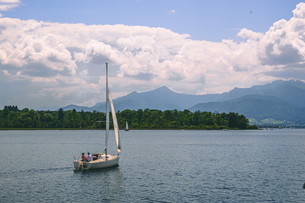 a sailboat in the middle of a lake with mountains in the background