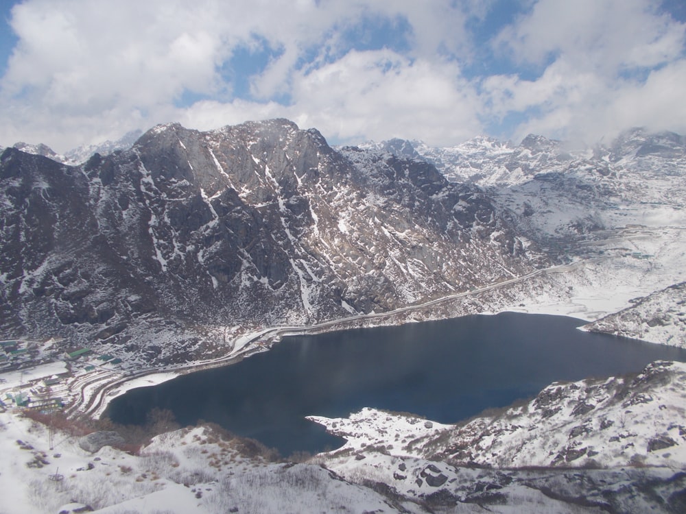 a snow covered mountain range with a lake in the foreground