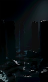 Tall, dark pillars rise from a misty, reflective surface in a dimly lit environment. The atmosphere is shrouded in mystery and shadows, with a subtle glow highlighting the tops of some pillars, suggesting an otherworldly ambiance.
