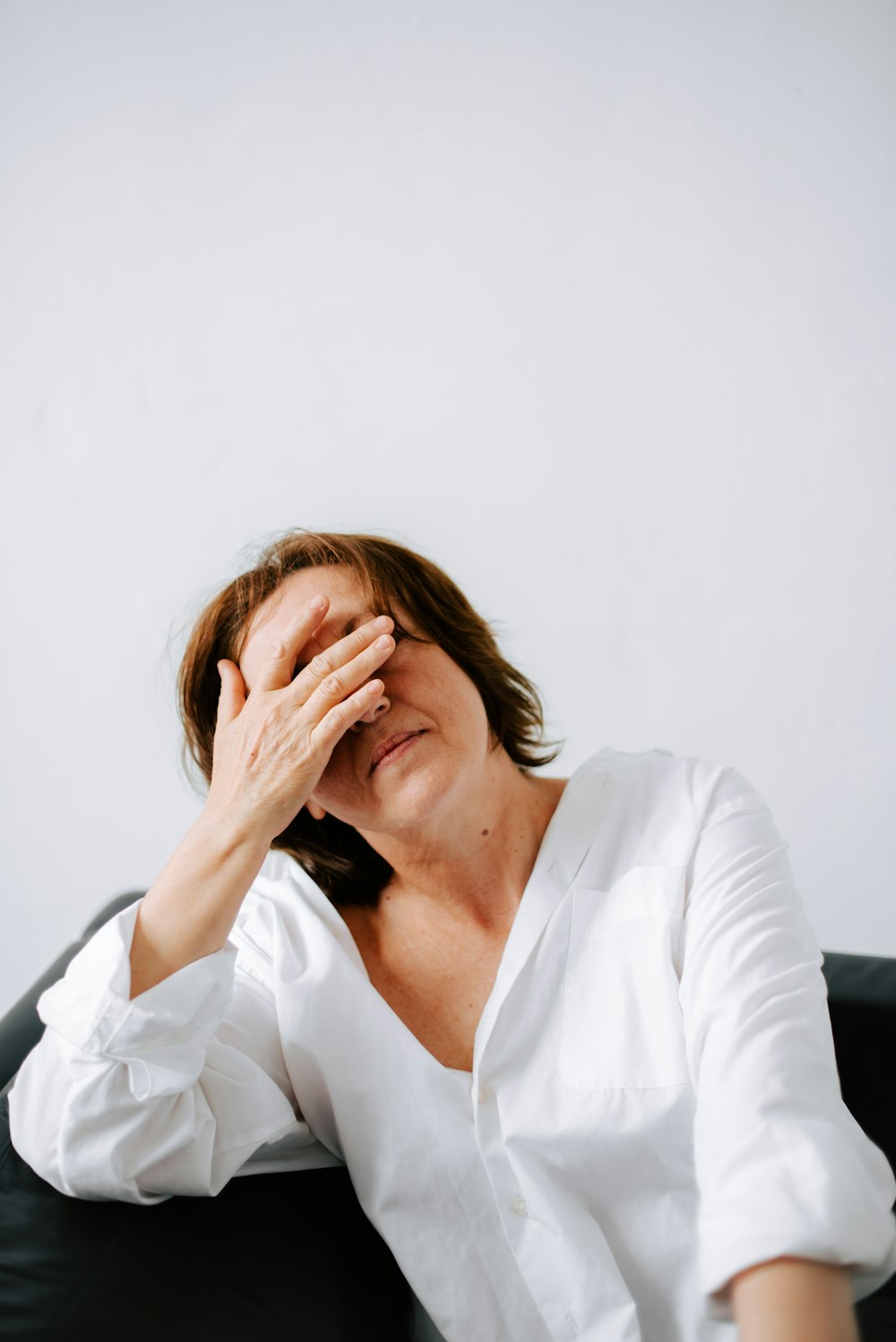 a woman sitting on a couch holding her hands to her face