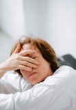 a woman laying in bed with her hands on her head