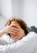 Close-up of a tired patient resting their head on their hand, showing fatigue and mental fog.