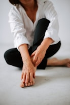 a woman sitting on the floor with her hands on her knees