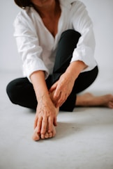 a woman sitting on the floor with her hands on her knees