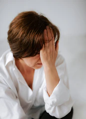 a woman sitting on a bed holding her head in her hands