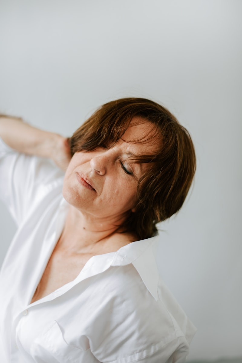 Active older woman in white shirt stretching her shoulder, demonstrating a senior foam rolling recovery routine