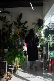 A friendly shop assistant advising a customer about plant care inside a cozy garden store.