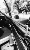 Close-up of a chauffeur’s hand opening a premium car door, in high-contrast black and white.