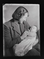 Mom tenderly holding a swaddled infant wrapped in a warm, earthy-toned wrap