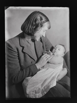Mom tenderly holding a swaddled infant wrapped in a warm, earthy-toned wrap