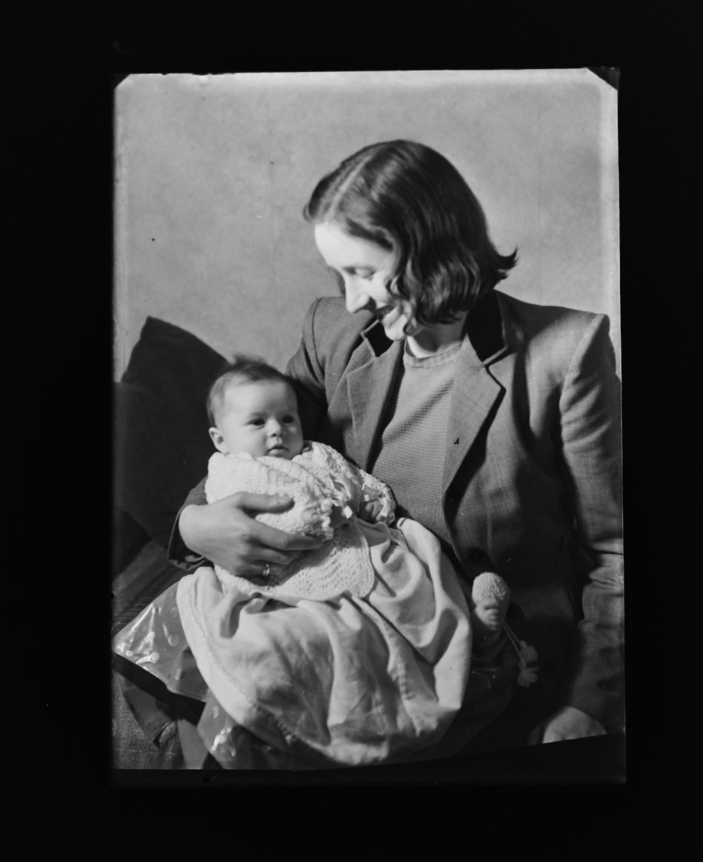 a black and white photo of a woman holding a baby