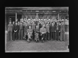 Group photo of the school's principal and teaching staff smiling in front of the school building.