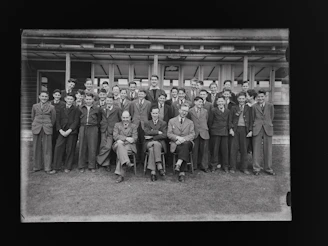 A group photo of diverse educators smiling warmly in front of the school building.