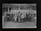 A group of young men and teachers are posing for a formal group photograph in front of a school building. The individuals are dressed in suits and ties, suggesting it is a school or academic setting.