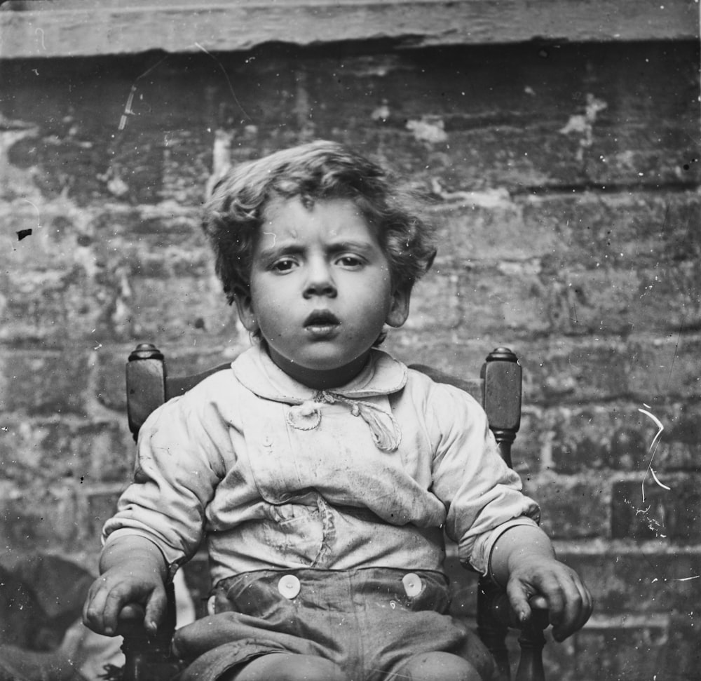 a young child sitting in a chair with a surprised look on his face