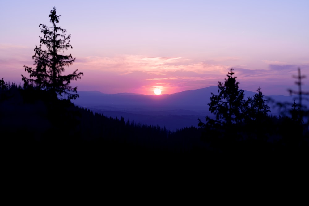 the sun is setting over a mountain range