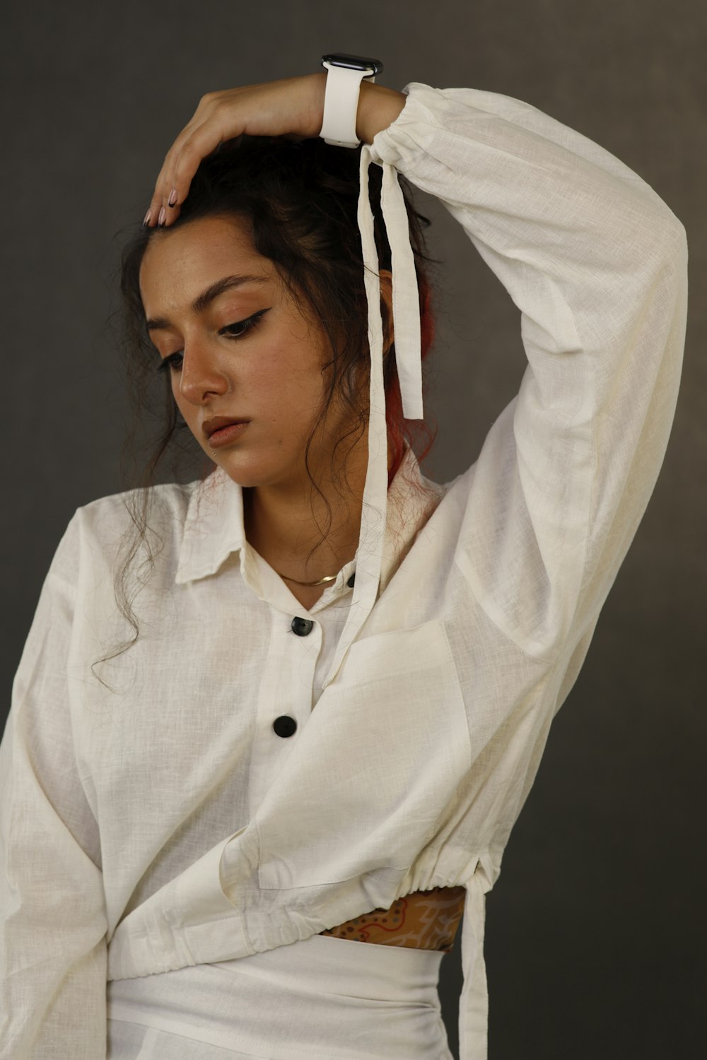 a woman in a white shirt is holding her hair