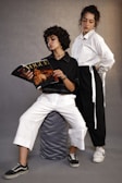 two young women sitting on a stool reading a magazine