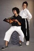 two young women sitting on a stool reading a magazine