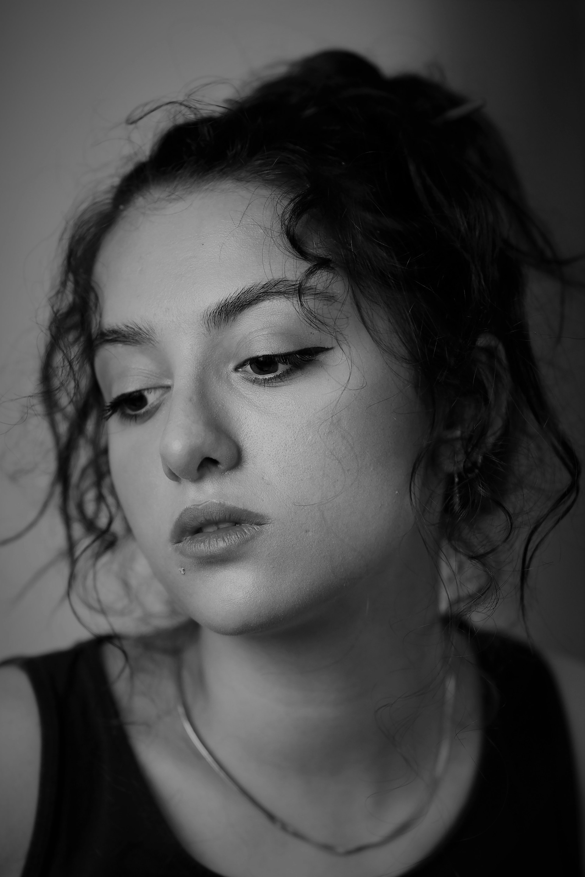 A striking black-and-white portrait capturing the subtle emotions of a young woman in natural light.