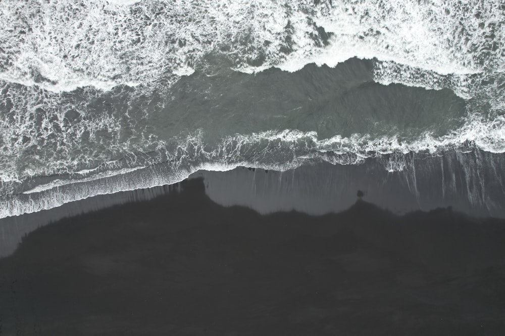 an aerial view of the ocean with waves crashing on the shore