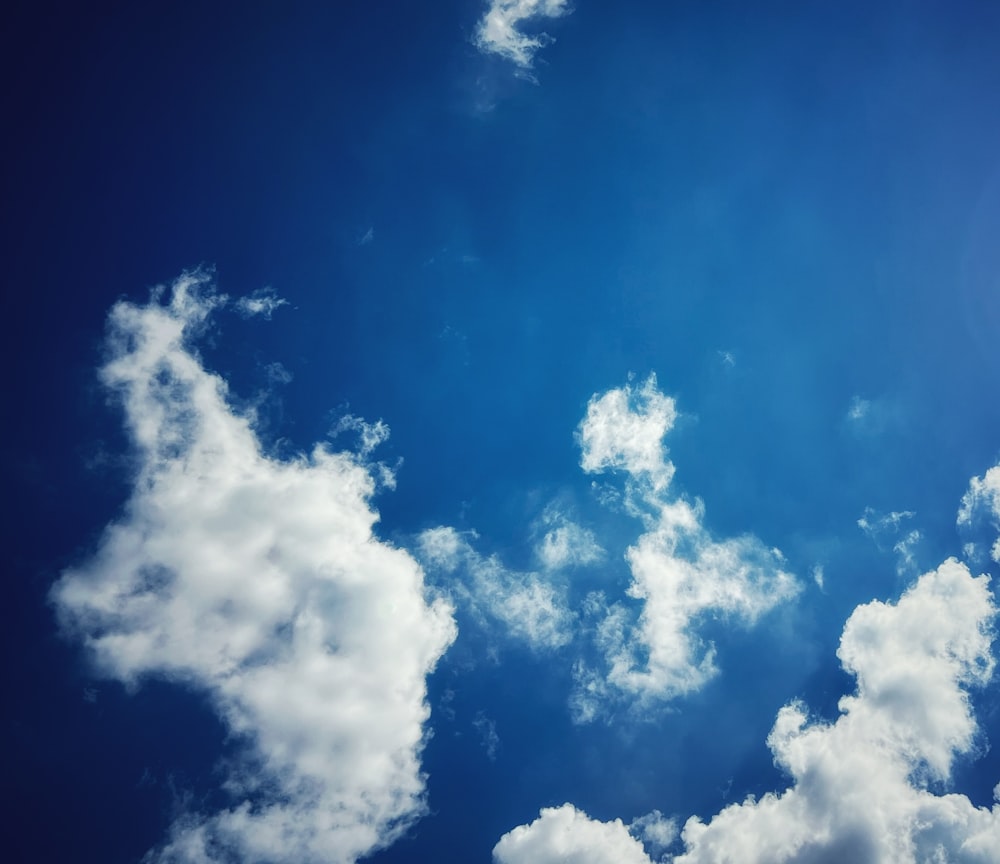 a plane flying through a blue sky with white clouds