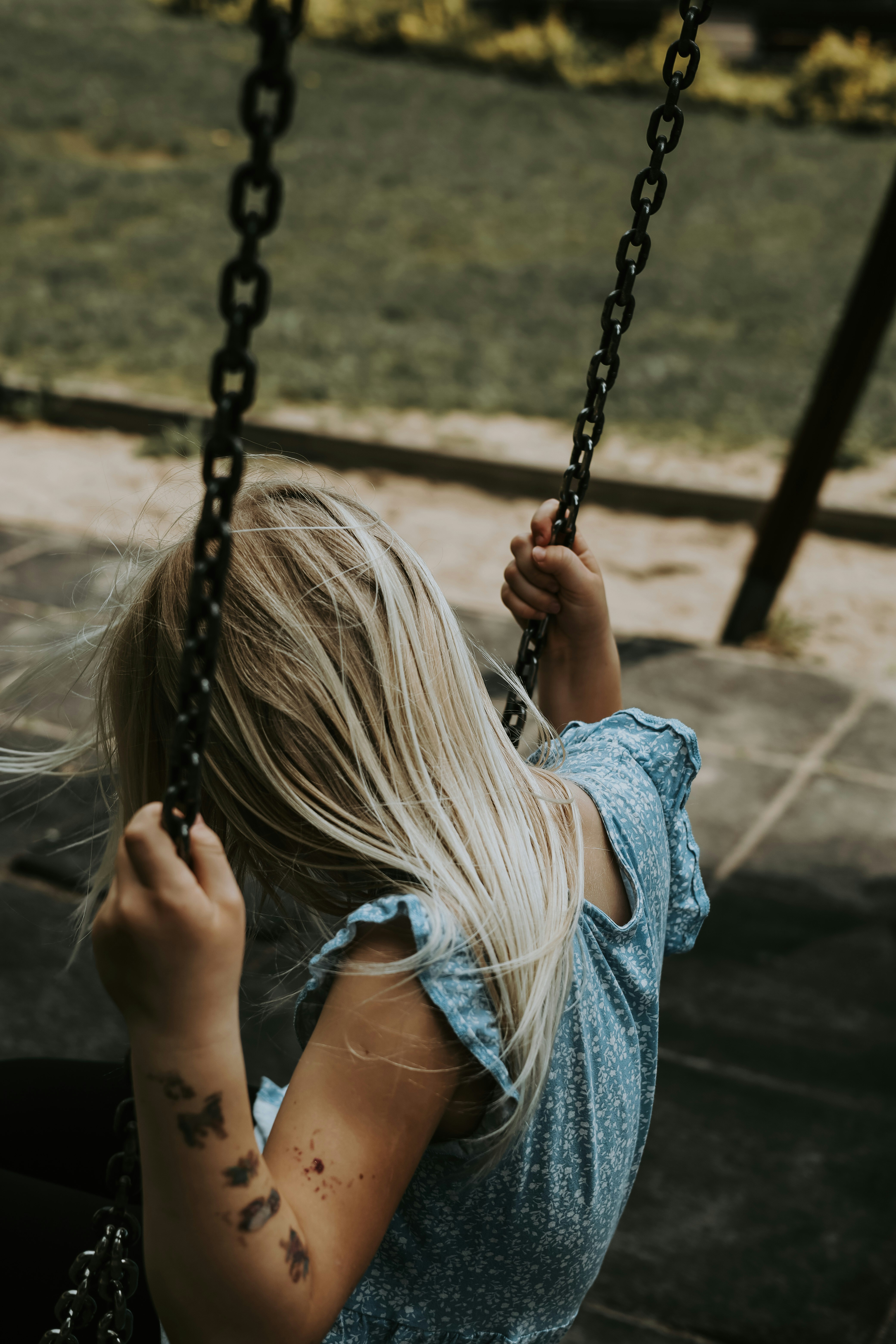 a woman sitting on a swing with a tattoo on her arm