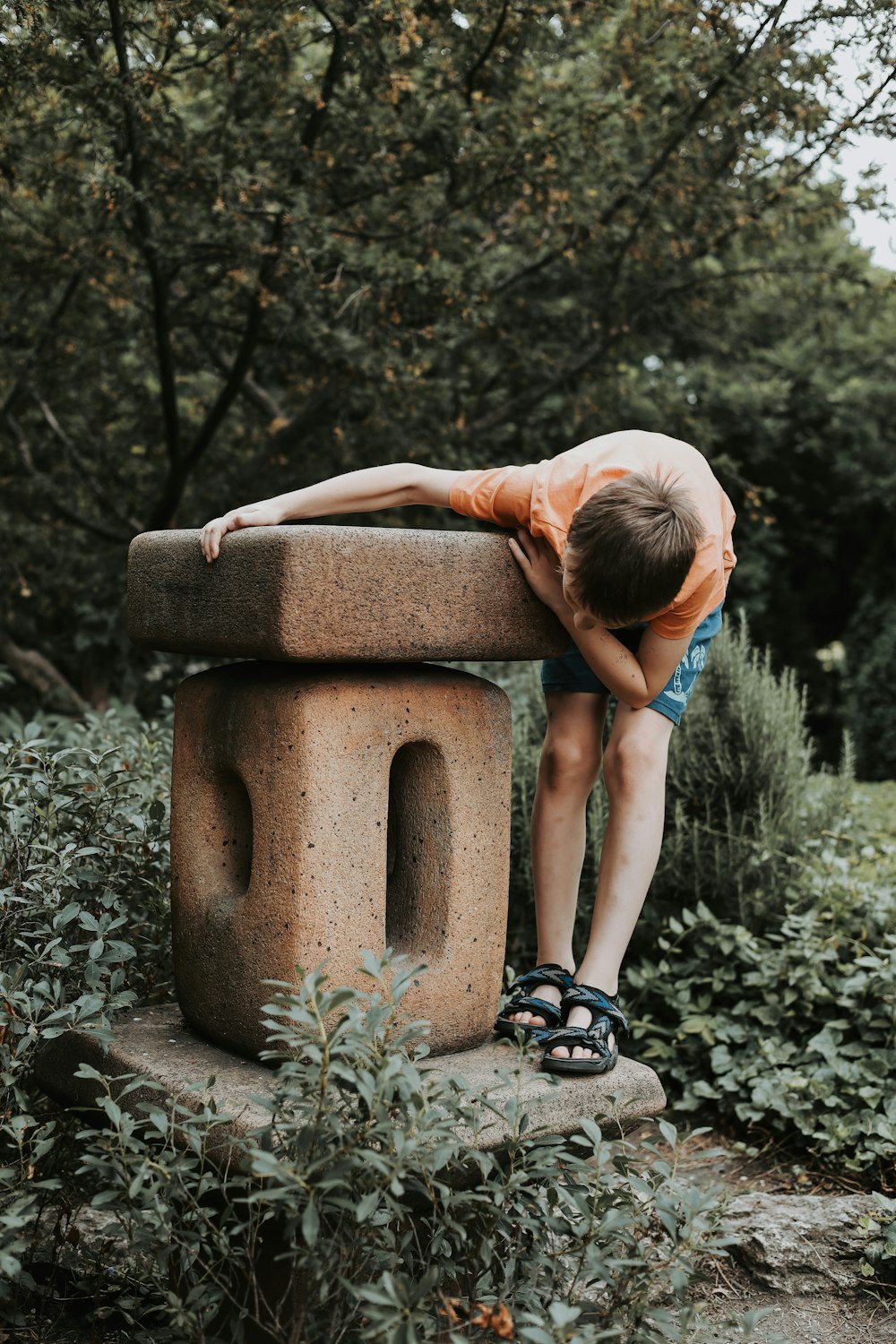 a young boy leaning on a stone bench