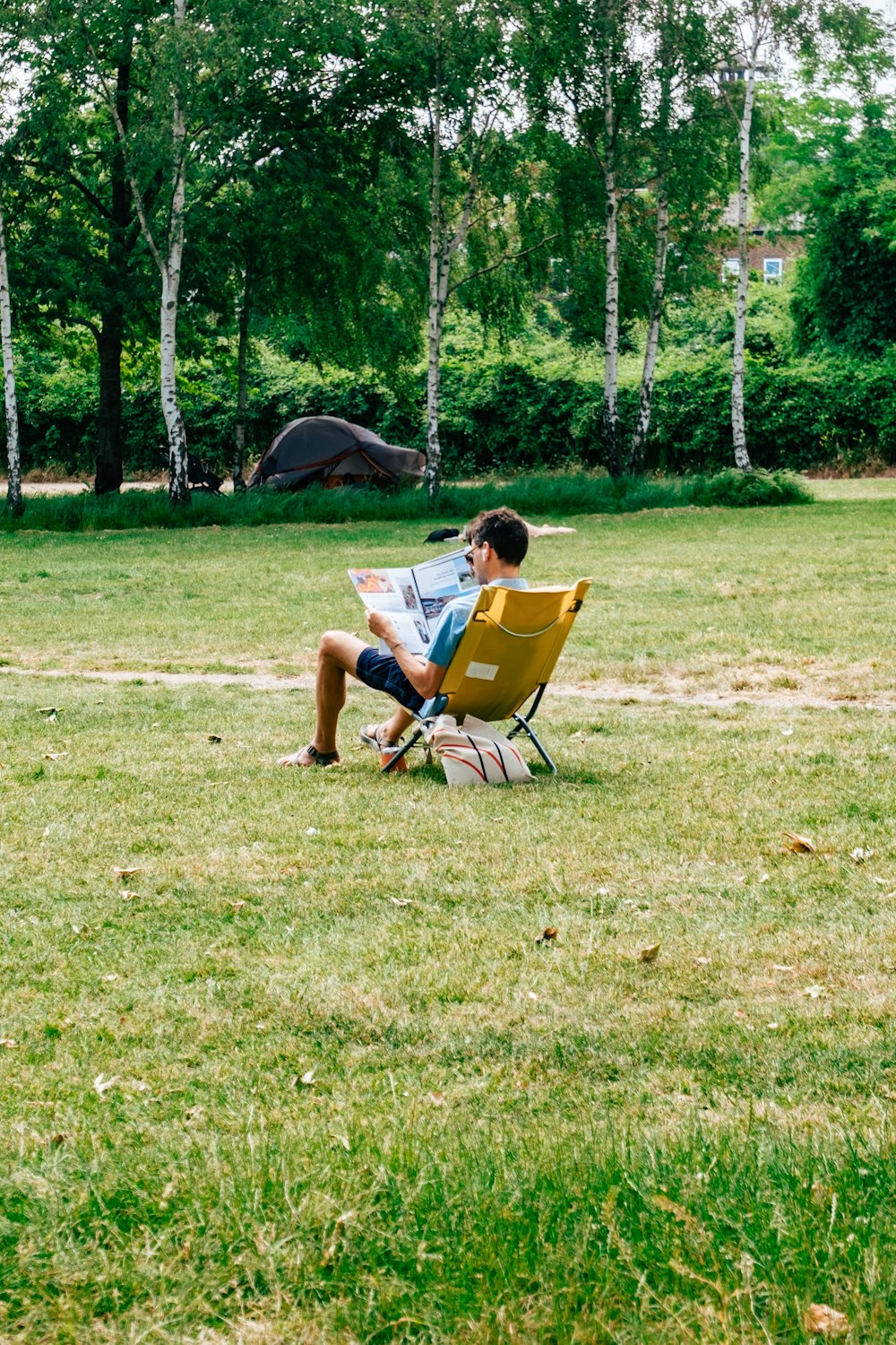 a man sitting in a chair reading a newspaper